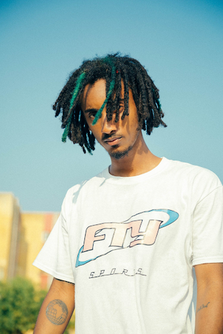 Young black man in t-shirt with short dreadlocks.
