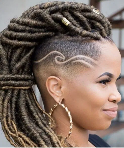 Woman with goddess locs in a mohawk with shaved sides and wavy lines.