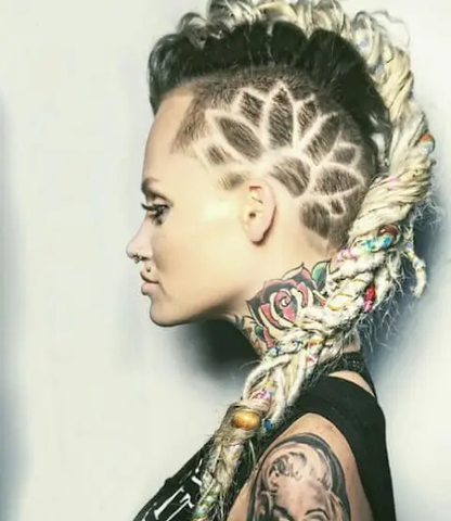 Side profile of woman with colorful locs in a mohawk with dark roots and a flower shaved into the sides.
