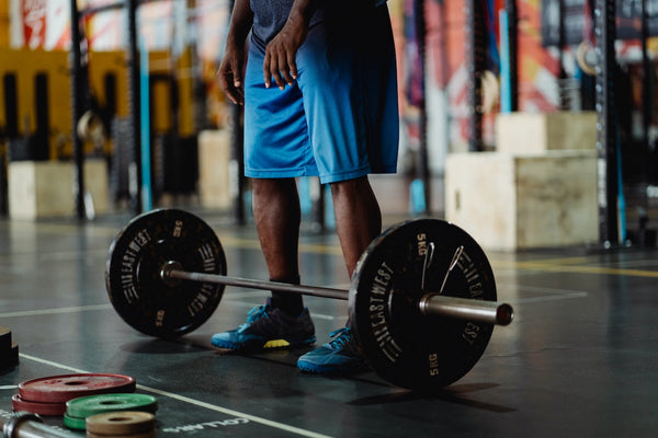 A barbell on the floor next to a man