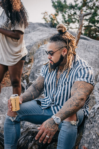 a man with dreadlocks next to a lake