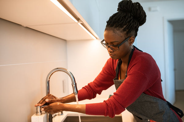 a woman with long dreadlocks washing her hands