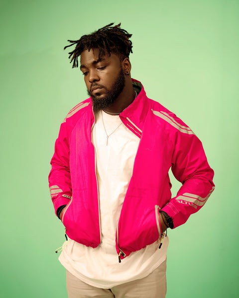 a man with starter locs wearing a pink track jacket