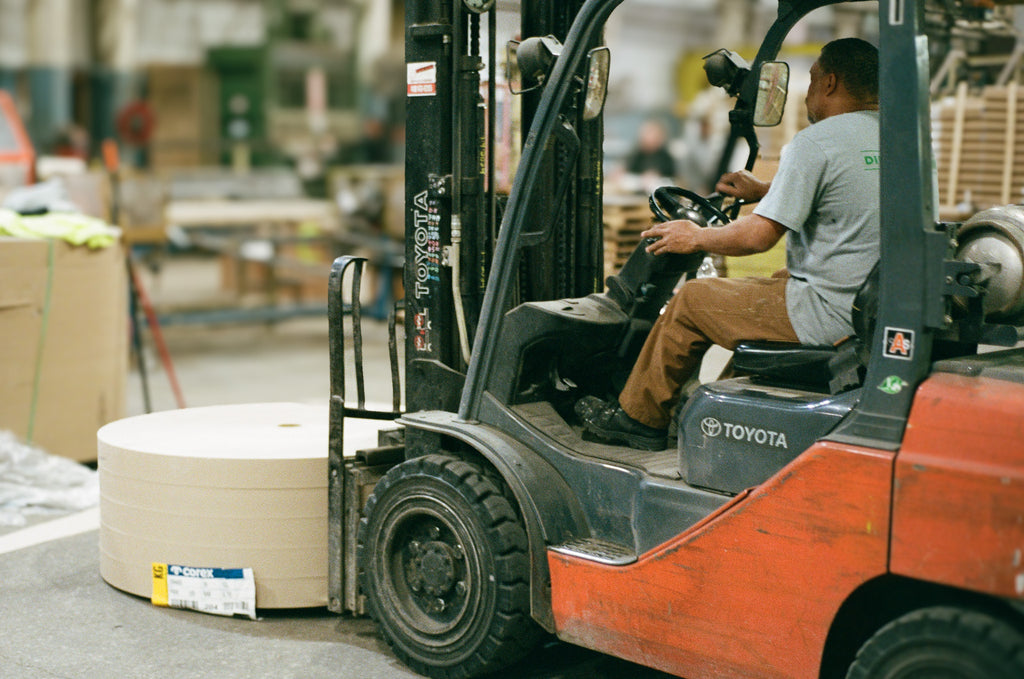 man on fork lift moving paper rolls