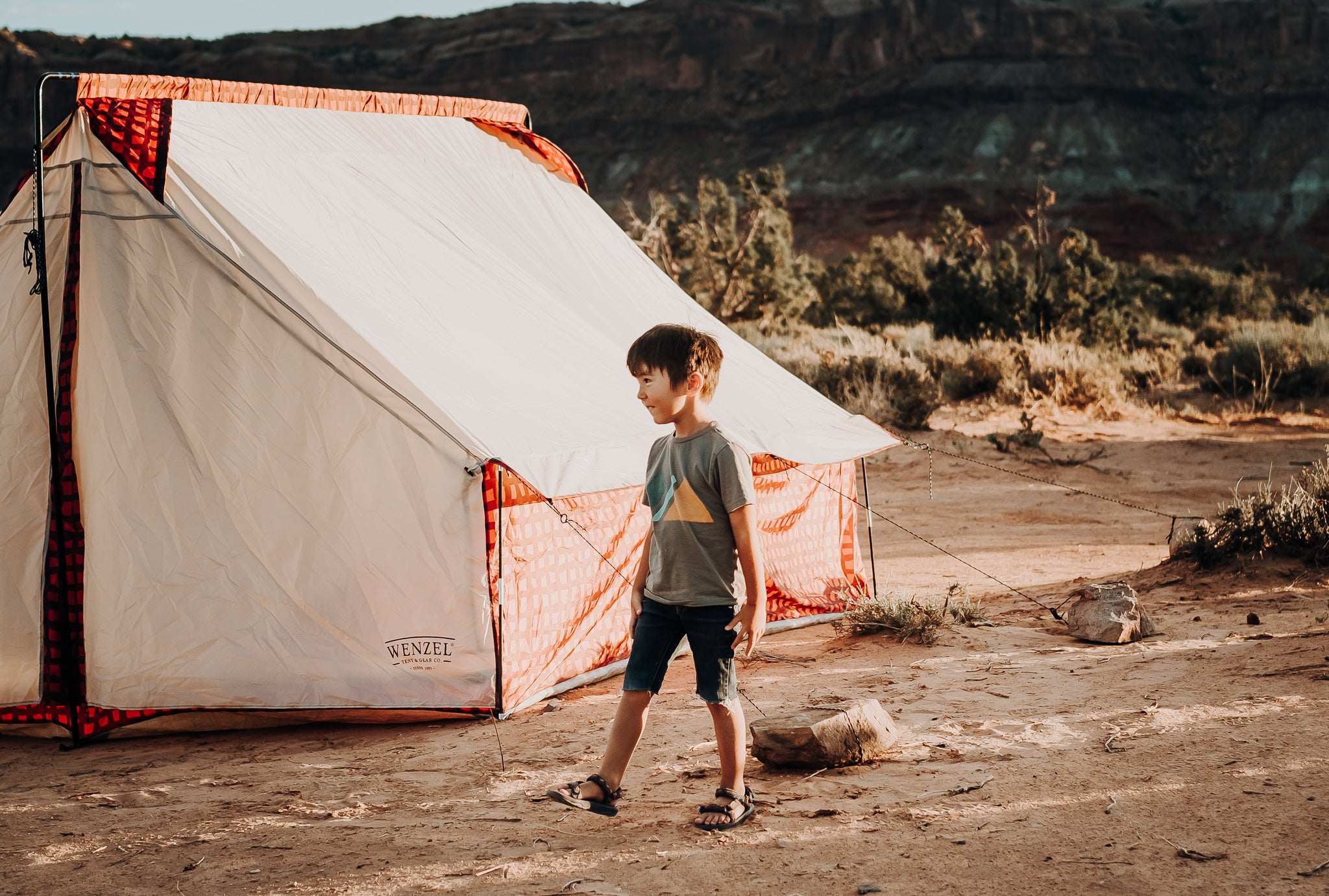 Kid standing next to a tent in the desert