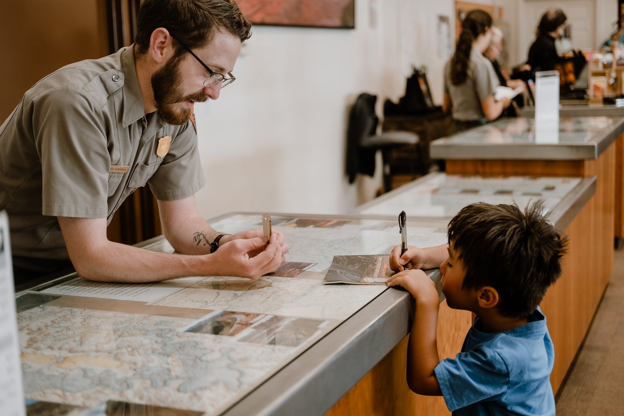 kid writing down information from a park ranger