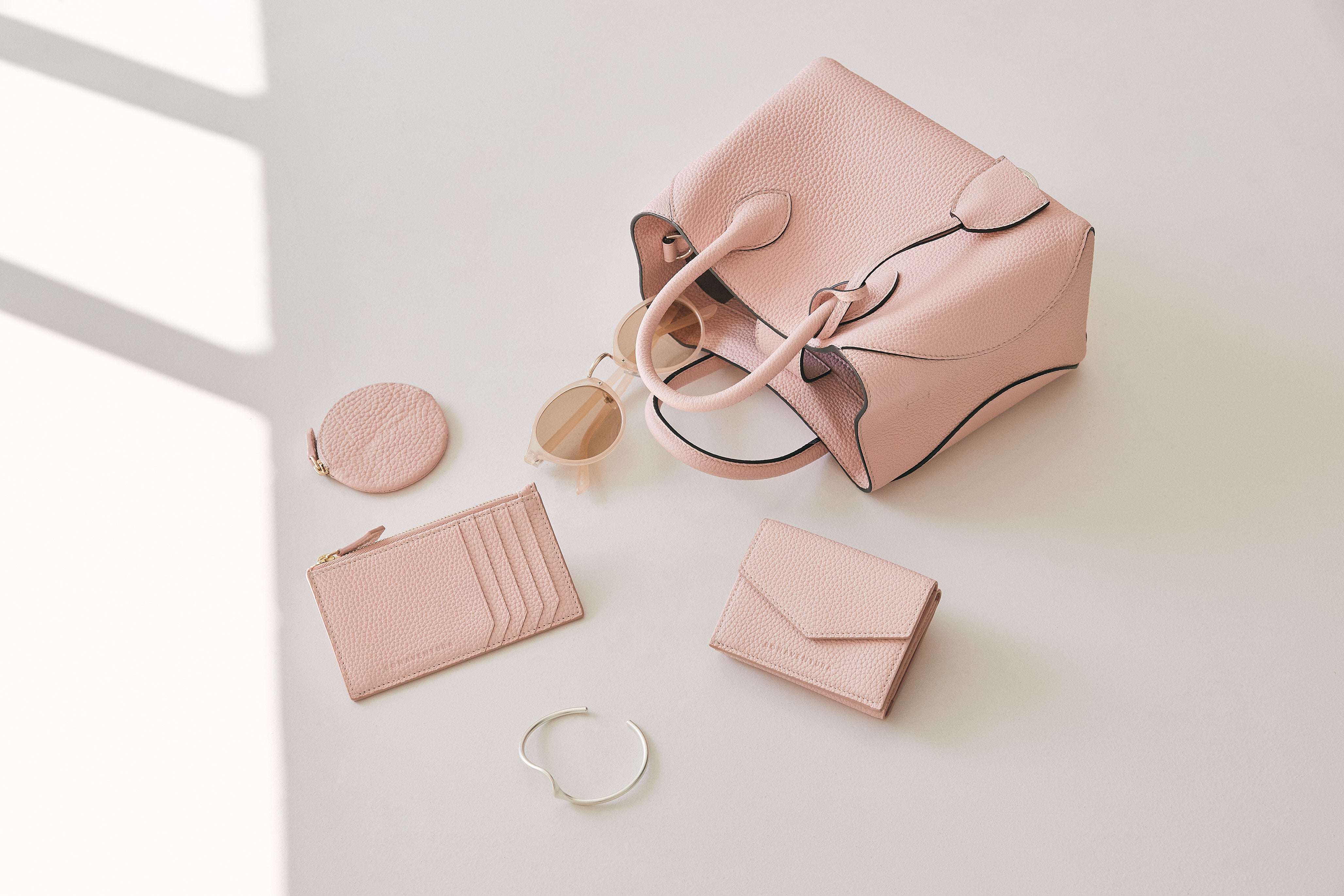 An elegant BONAVENTURA wallet, stylishly arranged next to trendy fashion accessories and a luxurious leather handbag.