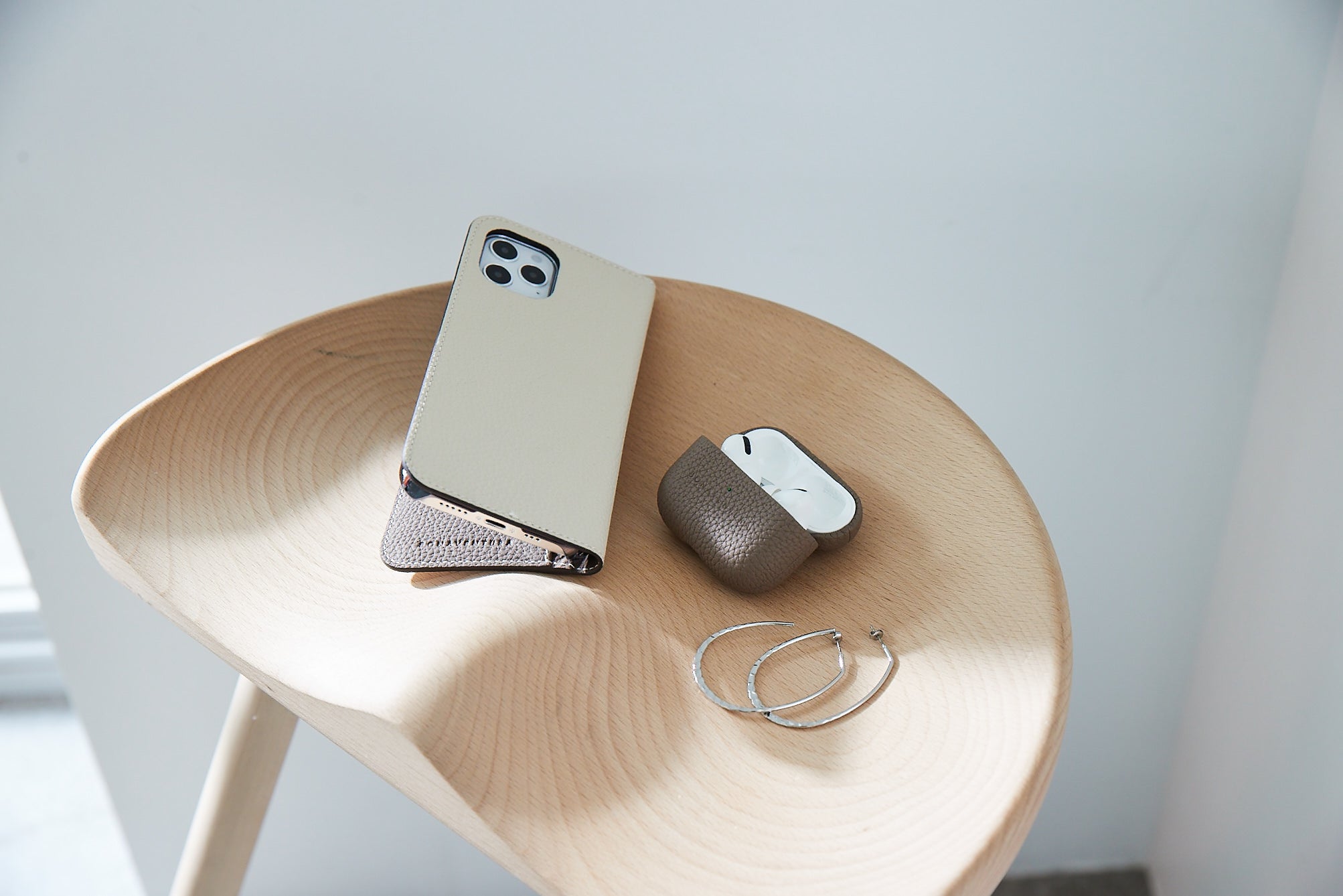 AirPods Pro 2 in BONAVENTURA Lederhülle auf einem Holztisch, Symbol für Eleganz und Qualität.