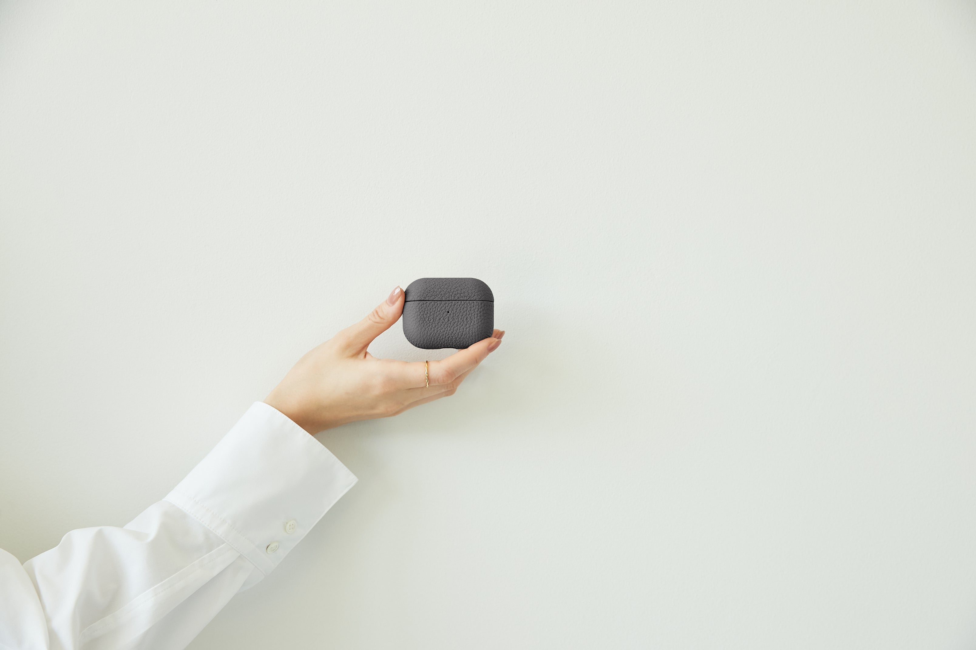 Stylish leather AirPods case in the hand of an elegantly dressed business person.