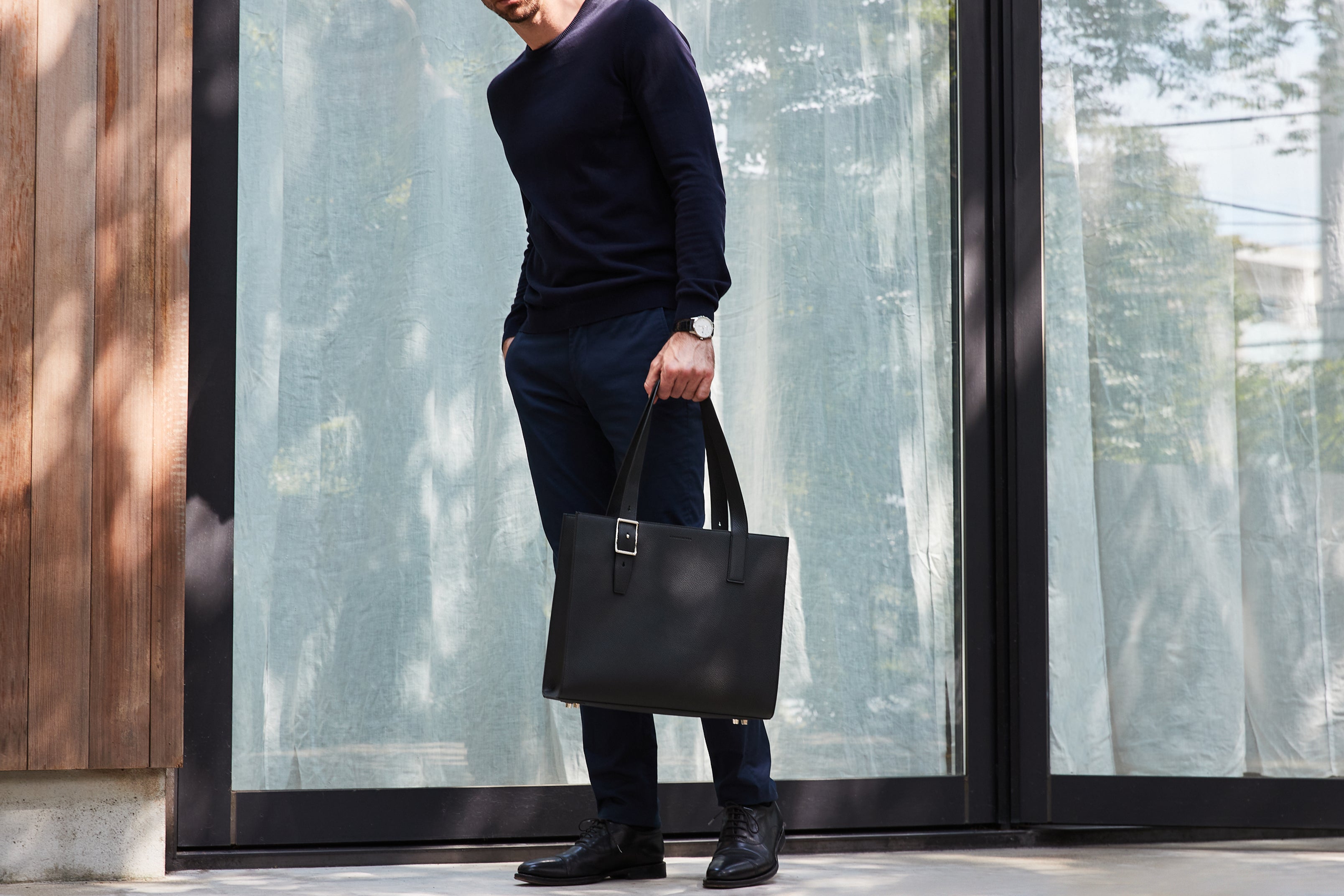 Stilsko oblečen moški z visokokakovostno usnjeno torbo za v pisarno.