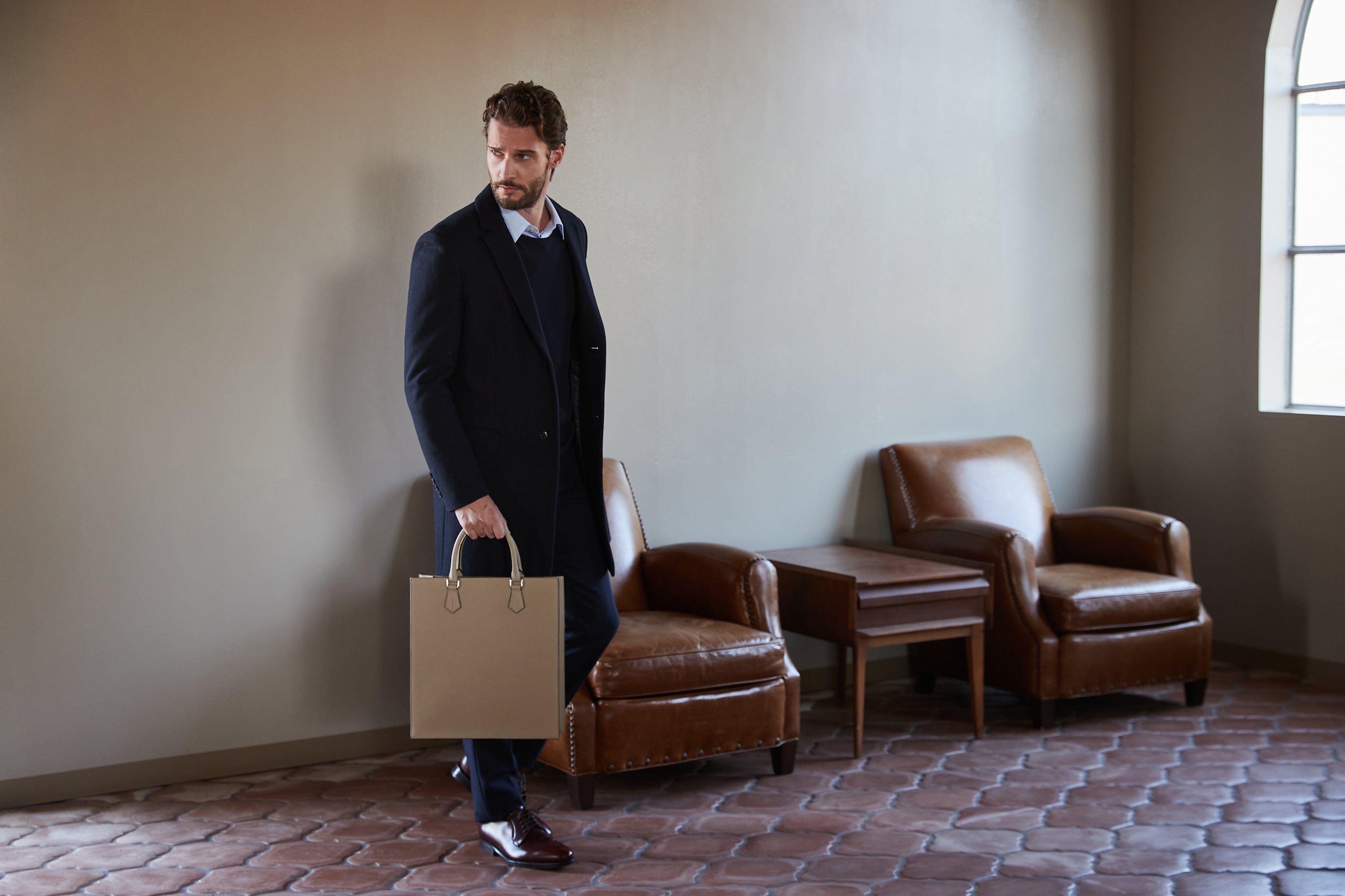 Um homem de negócios elegantemente vestido com uma mala de homem em pele de alta qualidade.