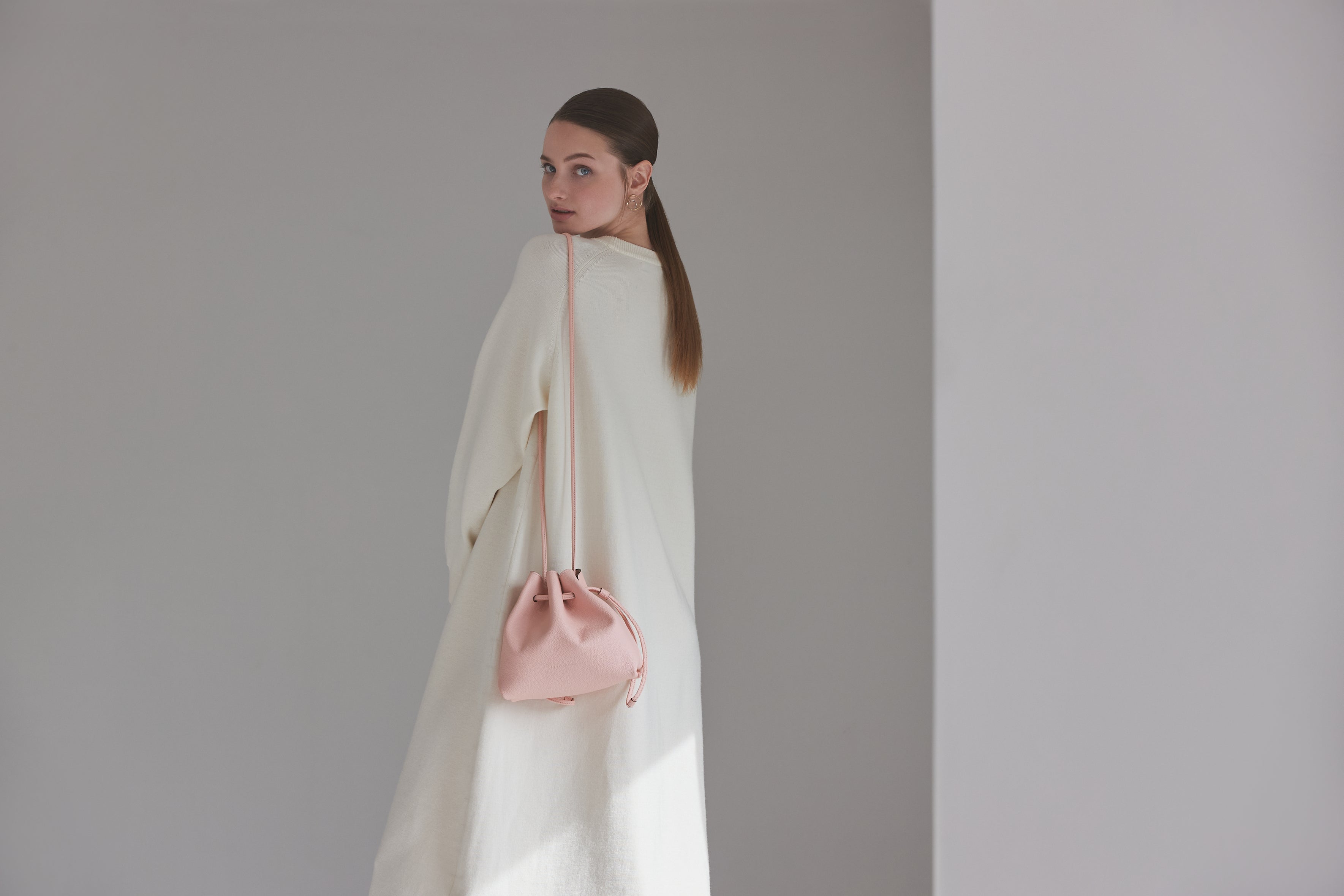 The modern and elegant Noa Drawstring Pouch is worn as a shoulder bag.