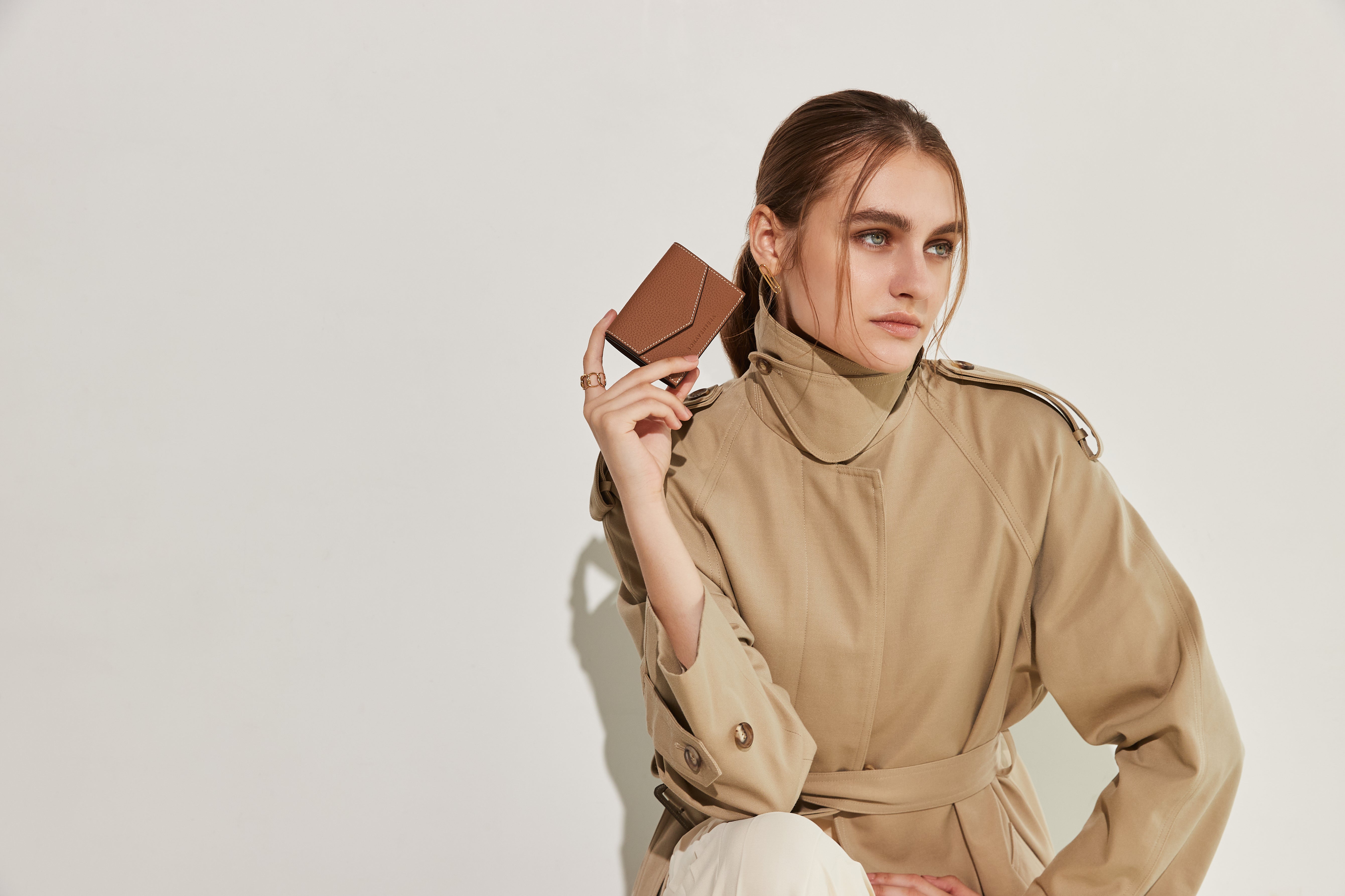 A woman holds a stylish small leather wallet in her hand