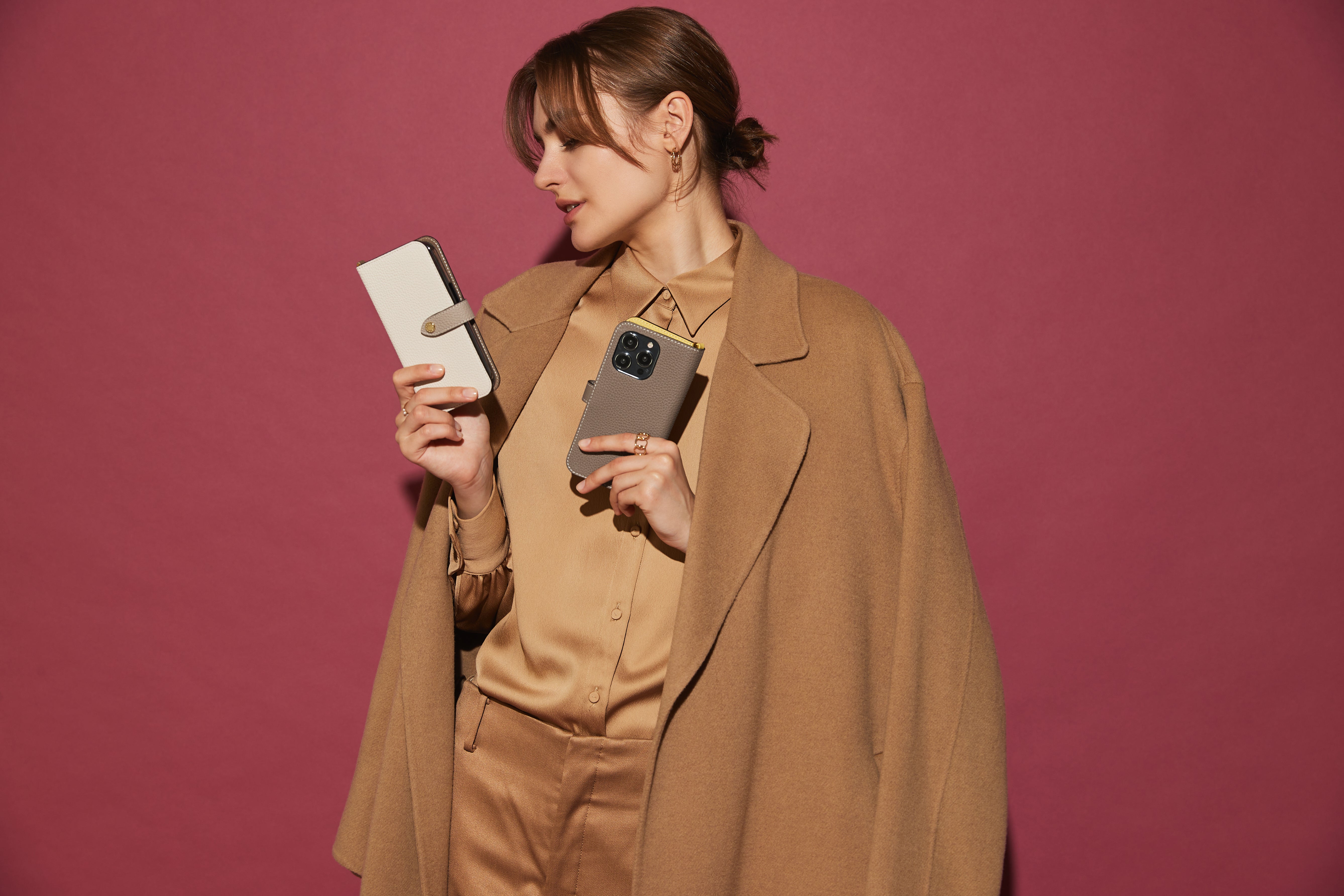 Elegante Frau hält iPhone 15 Pro Belted Diary Case und eine andere Lederhülle im Vergleich
