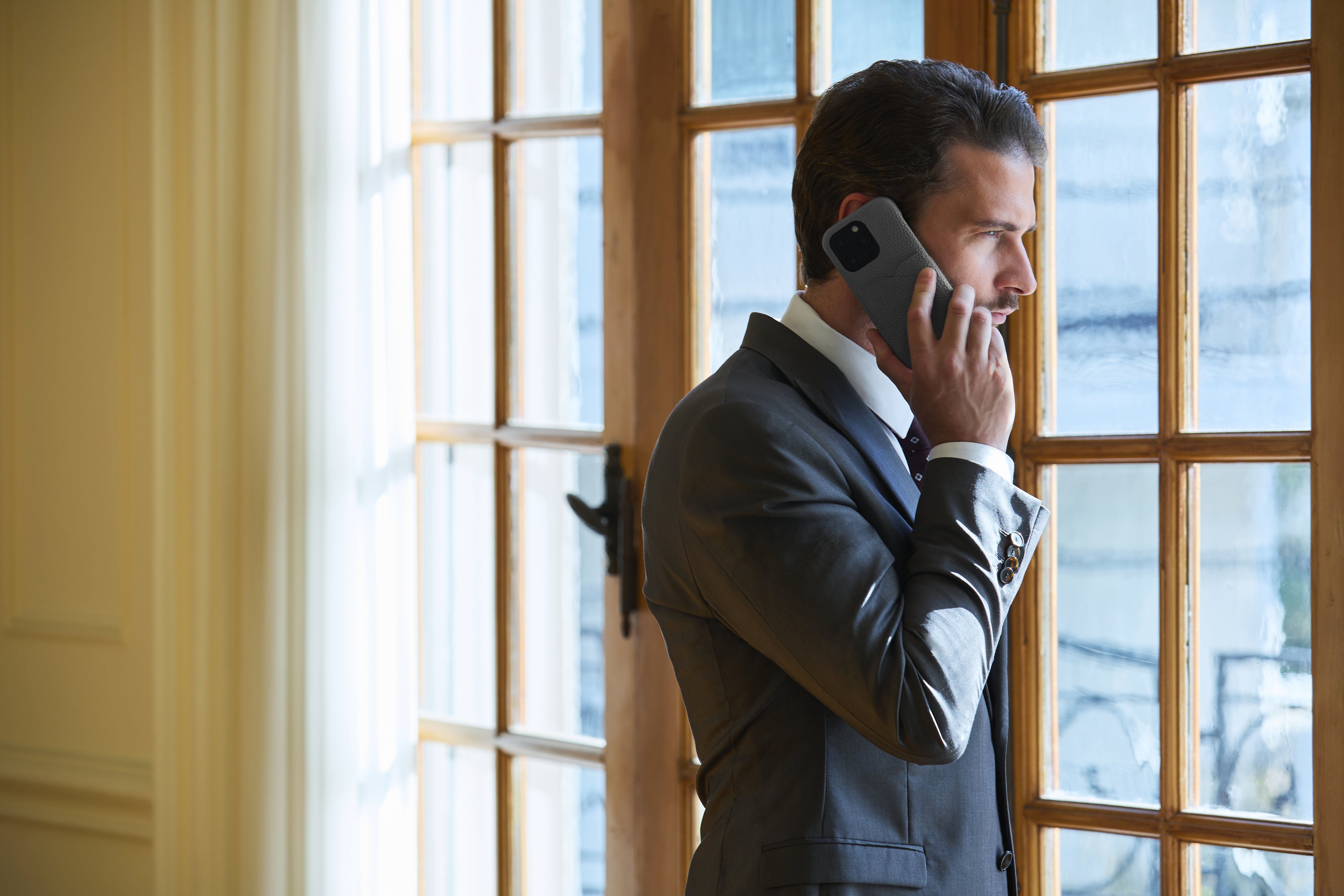 Um homem de negócios moderno faz uma chamada telefónica com o seu iPhone na capa de pele de alta qualidade da BONAVENTURA