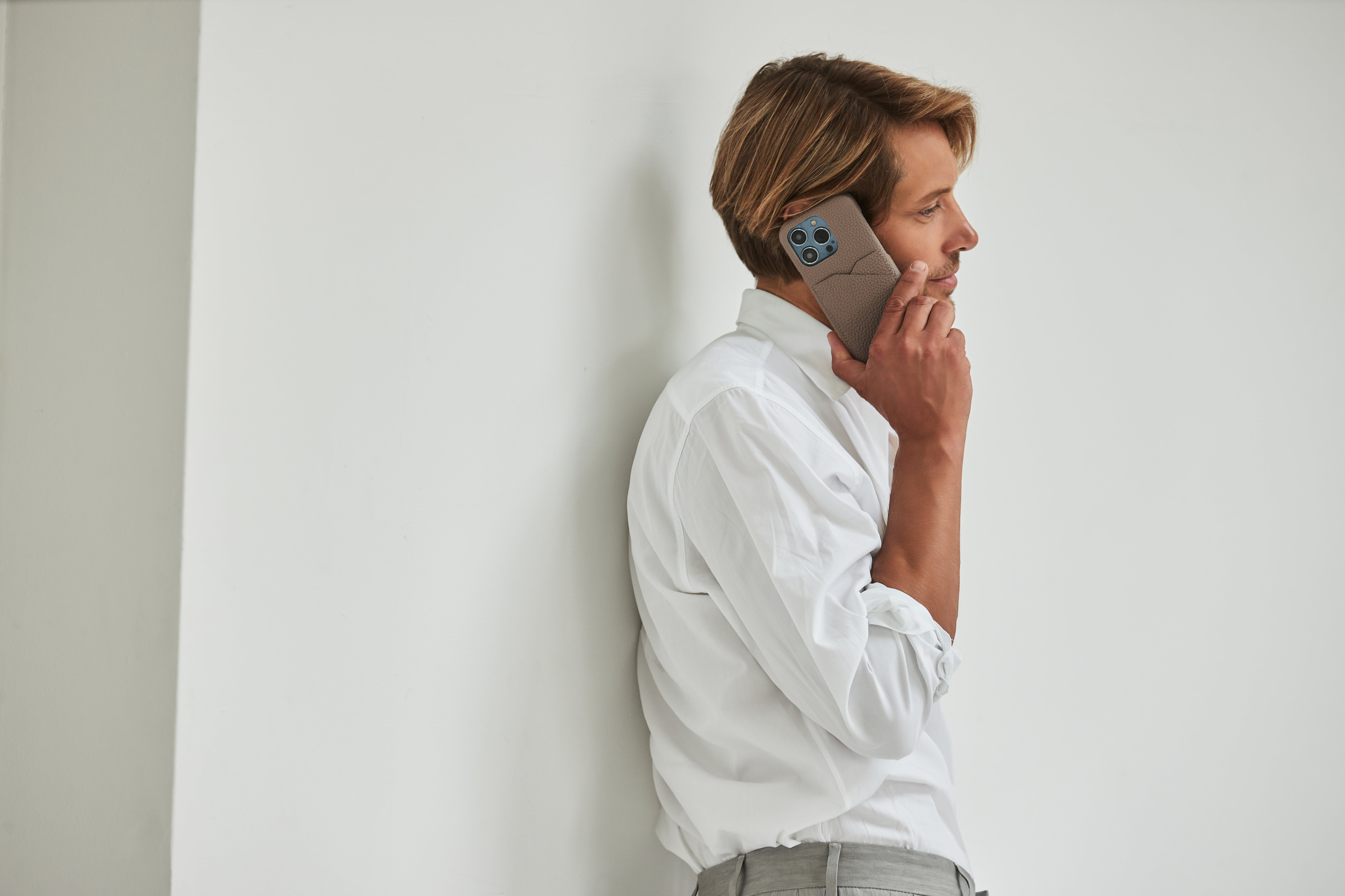 A stylishly dressed man holds an iPhone 15 leather case.