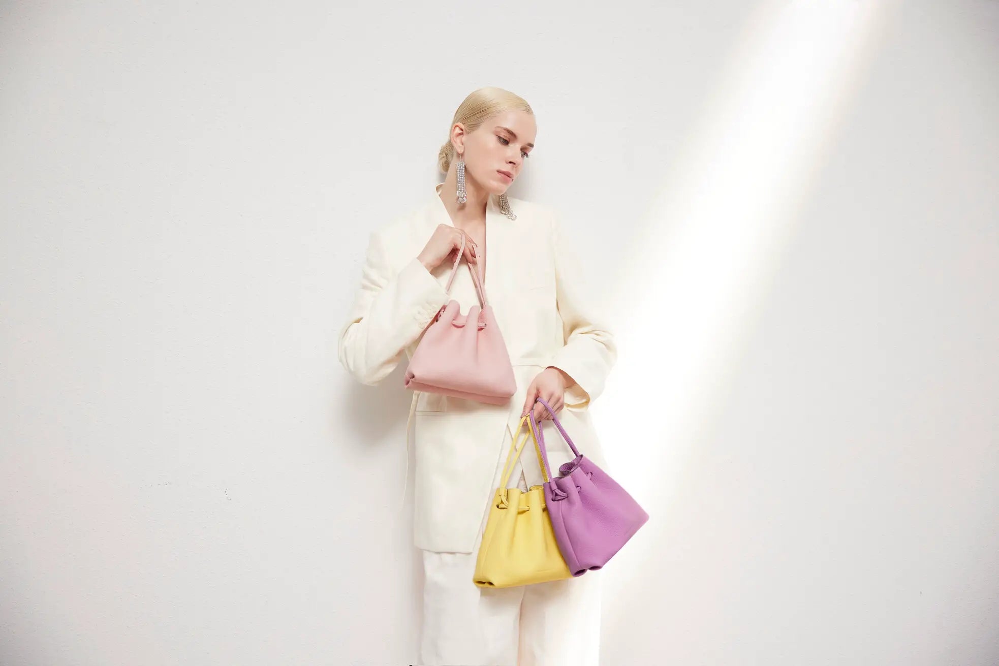 Stylish woman holds bucket bags in different spring colors.