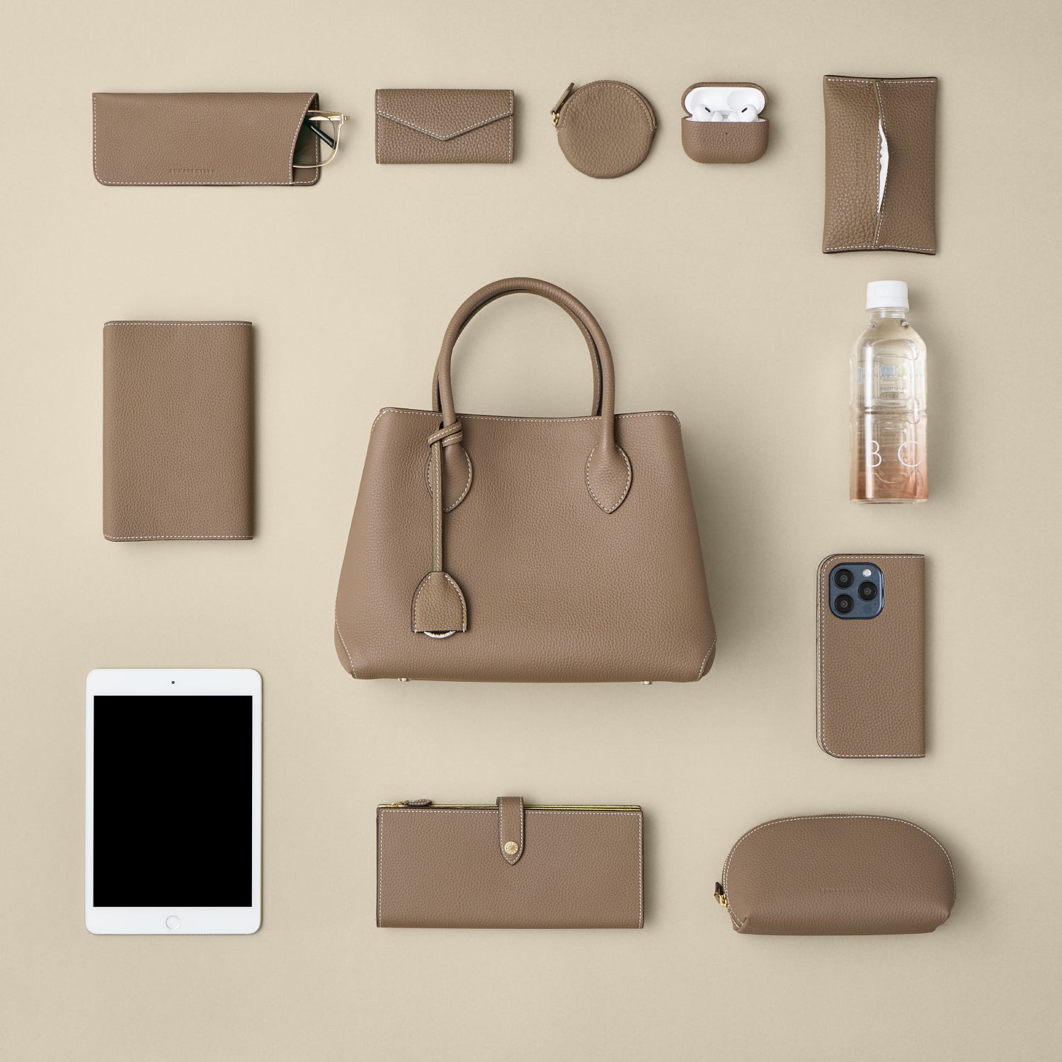 Tuvplāns Mia Tote Bag Small uz galda, kurā redzama somas ietilpība ar daudziem atbilstošiem ādas izstrādājumiem.