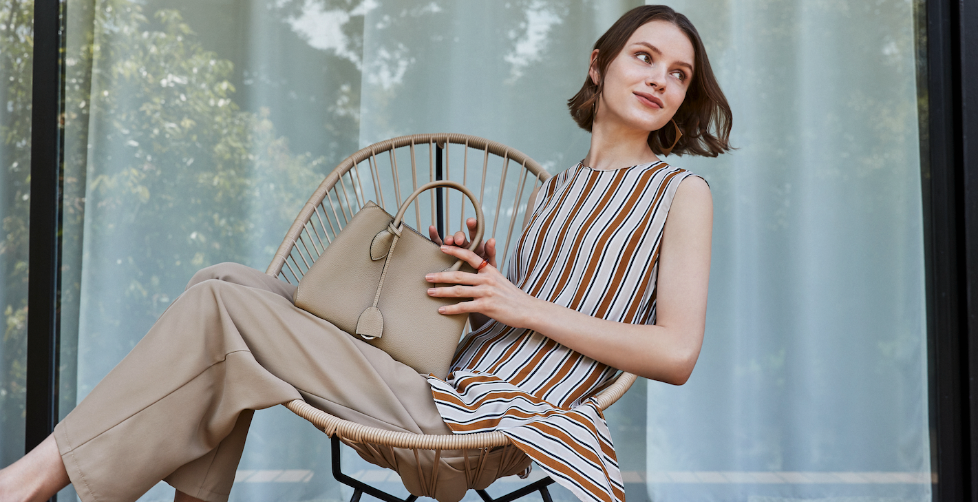 Una mujer elegante sostiene feliz un lujoso bolso de piel plena flor de alta calidad.