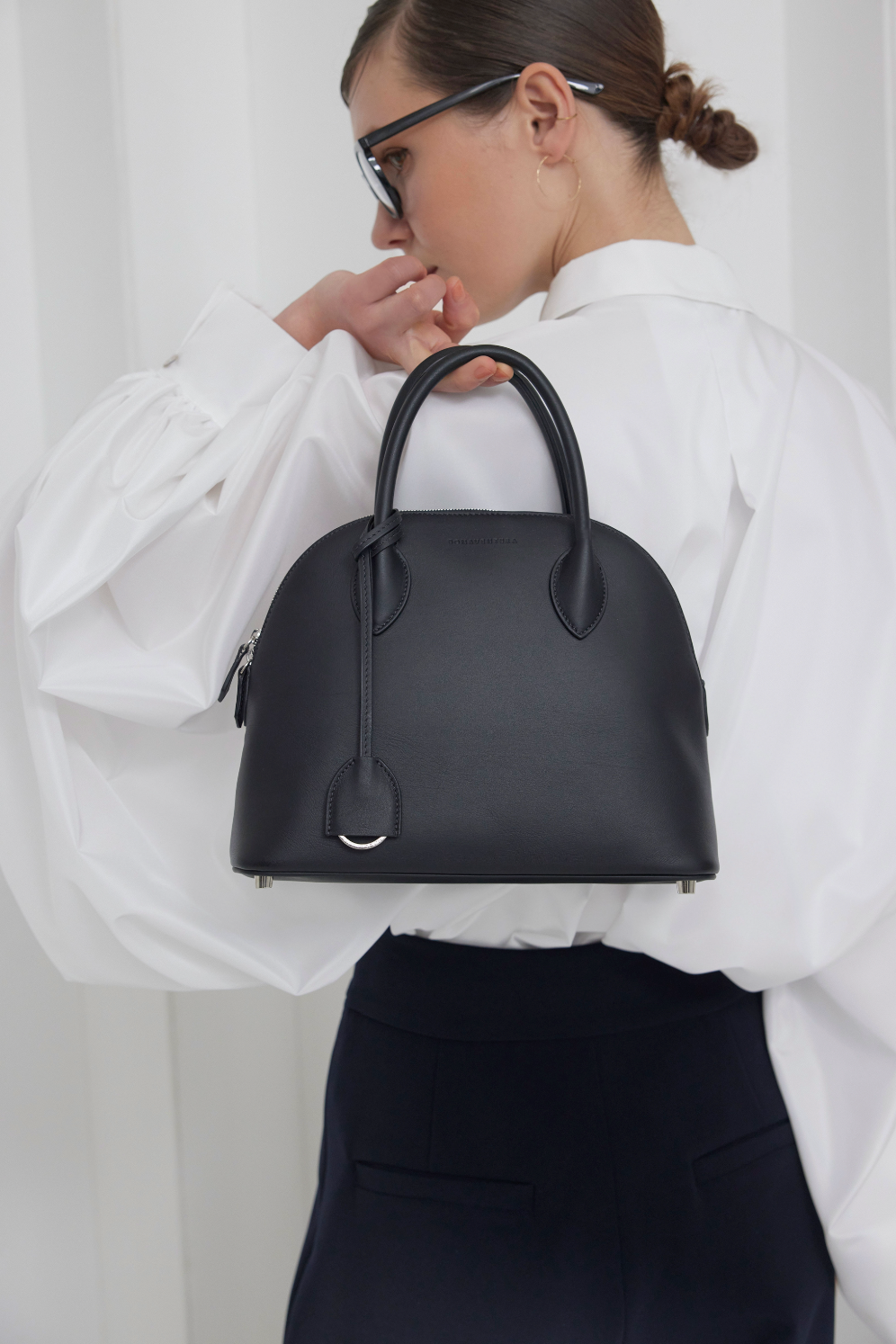 Stilvolle Frau trägt eine große Emma Bag, die perfekt für den Büroalltag ist.