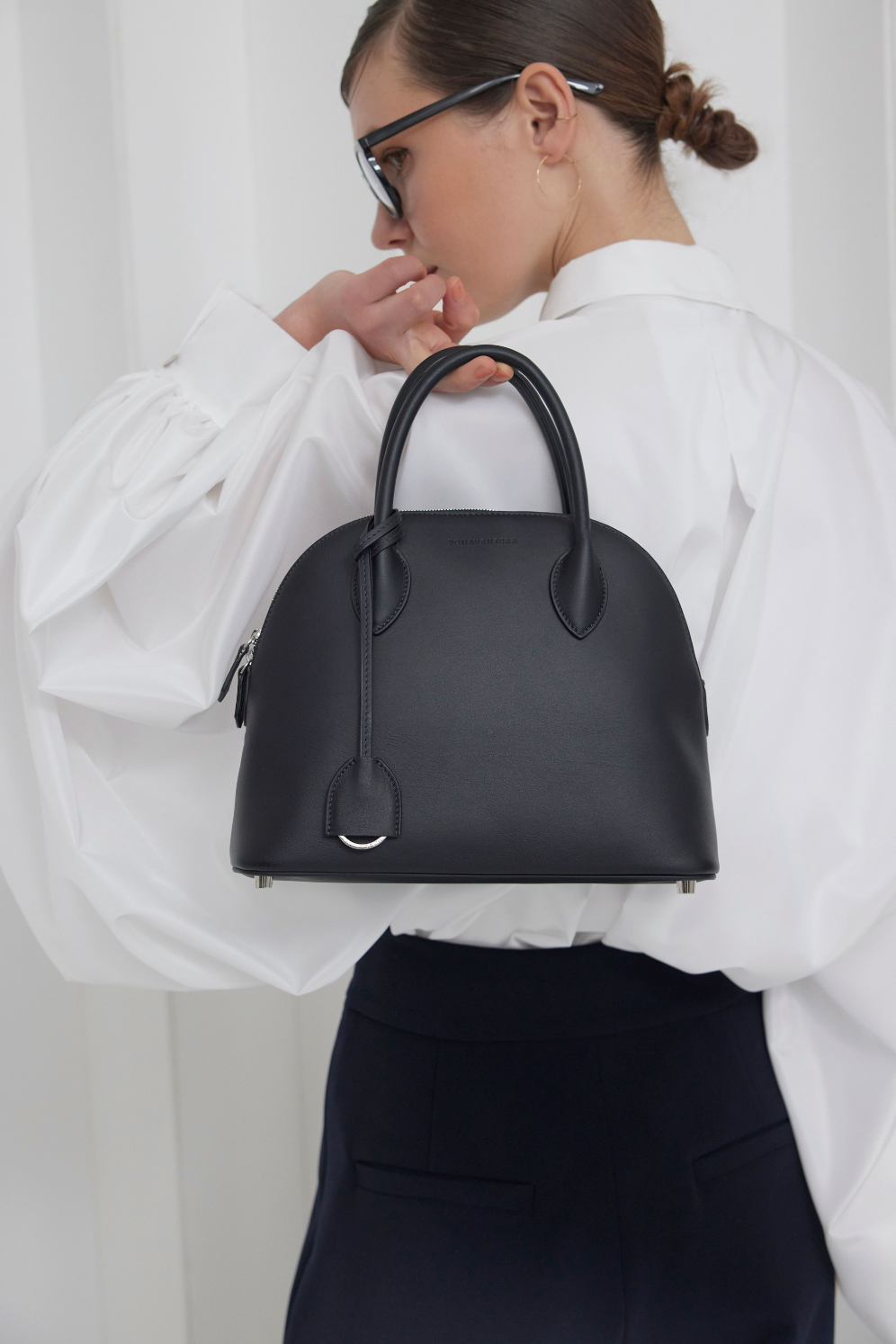 Una donna elegante porta con sé una grande borsa Emma, perfetta per la vita quotidiana in ufficio.