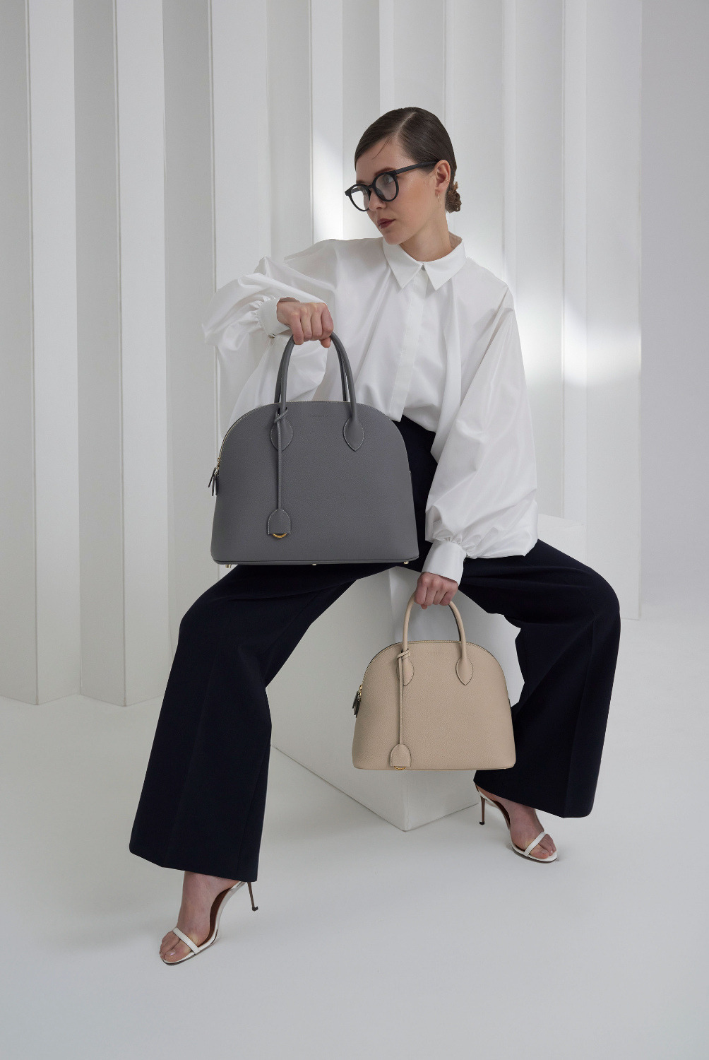 Elegant businesswoman presents two sizes of the Emma Bag, the perfect business bag.