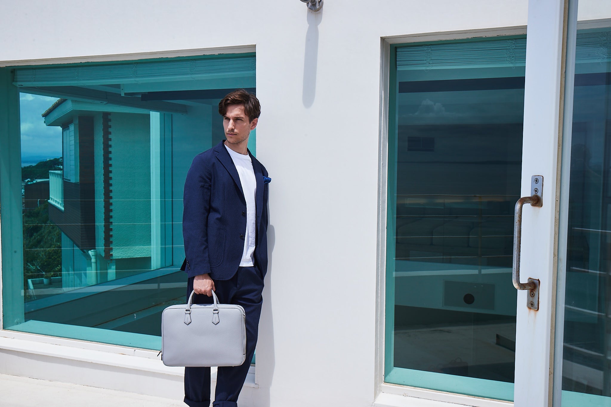 En stilfuldt klædt mand bærer en businessmappe i læder af høj kvalitet til kontoret.