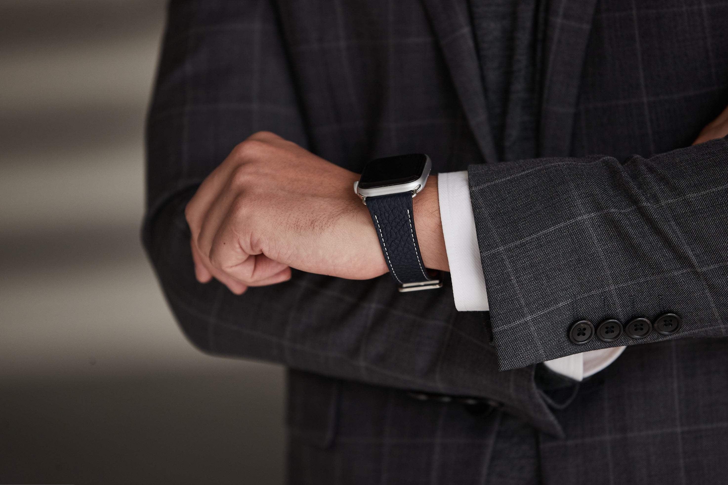 Un elegante uomo d'affari con una fascia in pelle BONAVENTURA di alta qualità per il suo Apple Watch.