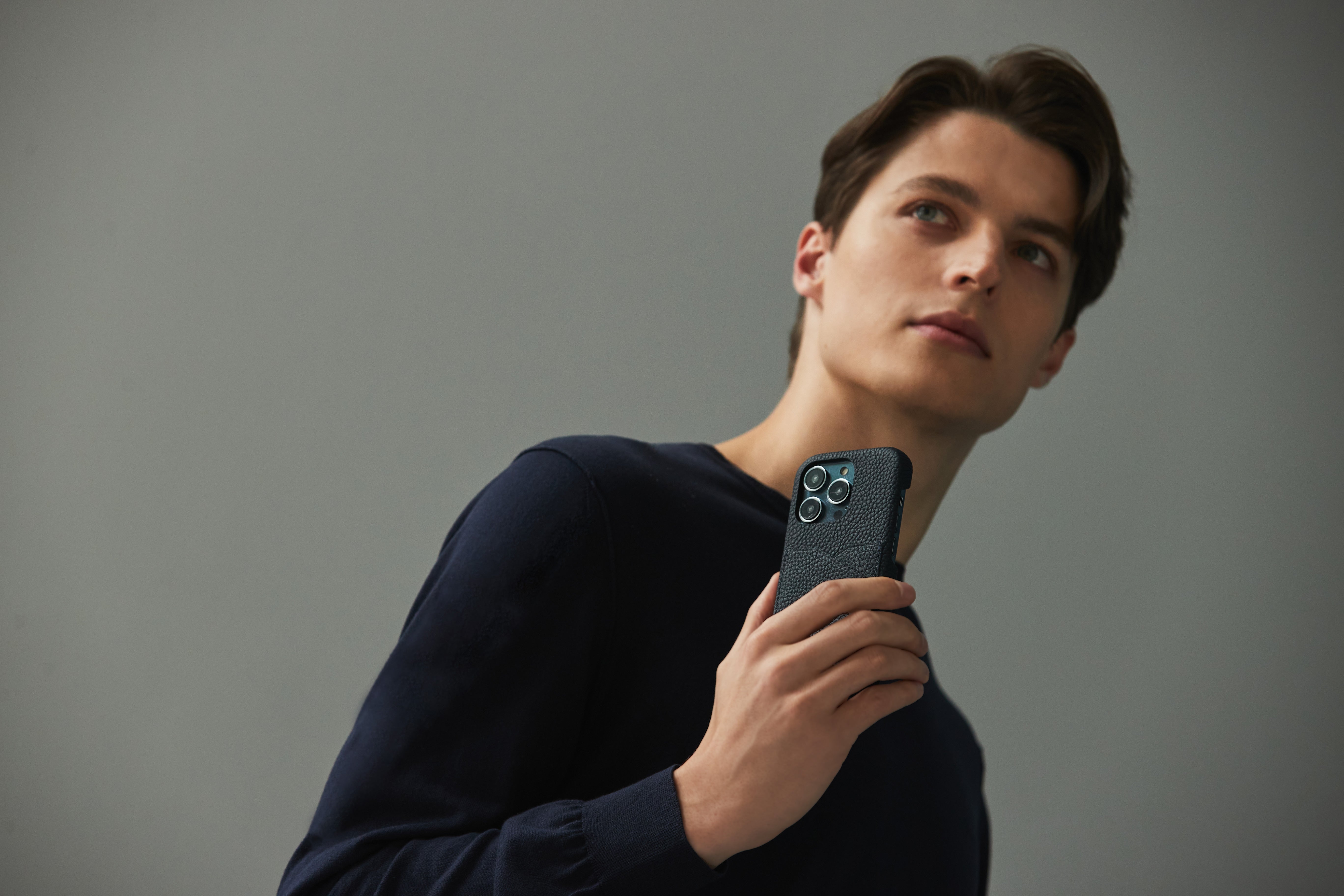 An elegant man holding an iPhone 15 in a high-quality BONAVENTURA leather case.