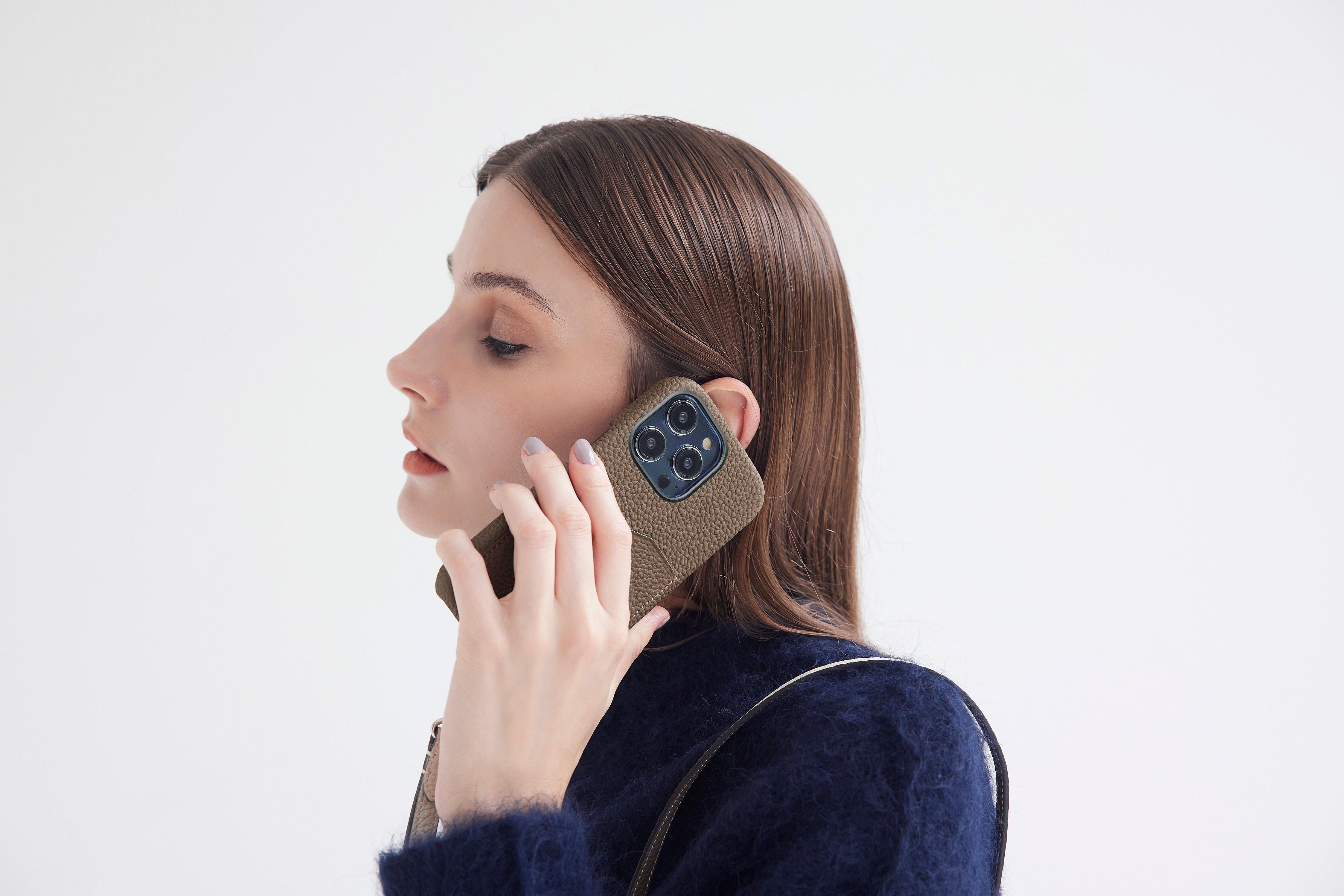 A woman holds the iPhone 15 Pro in a noble leather case.