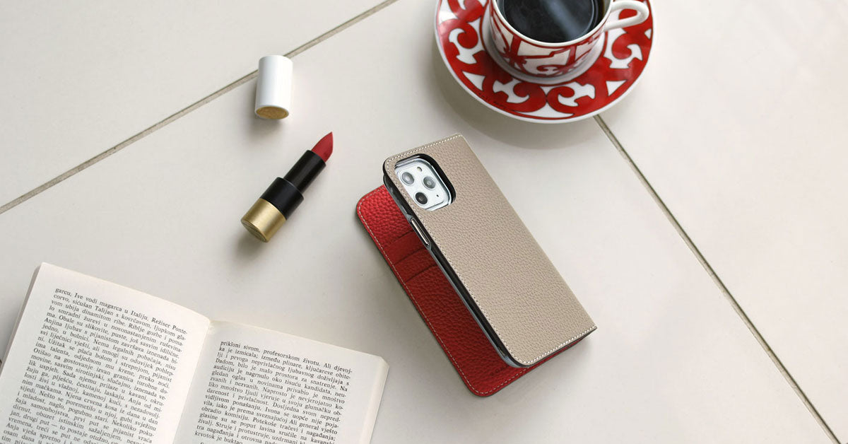 Elegante funda de piel BONAVENTURA junto a un iPhone sobre una mesa.