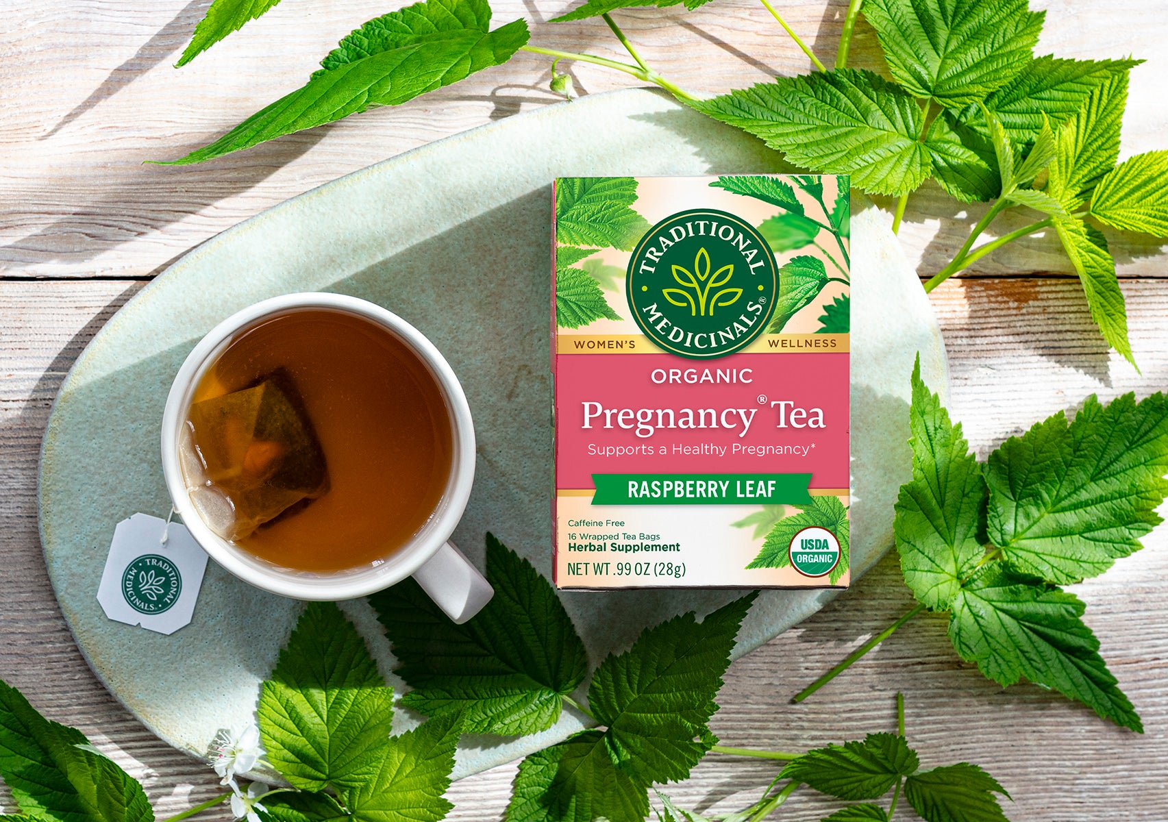 Organic Pregnancy Tea Brewing in Cup Surrounded by Herb Leaves