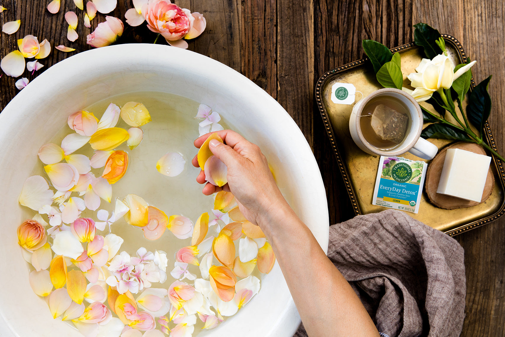 Rose petals floating in large bowl of water with EveryDay Detox tea on table