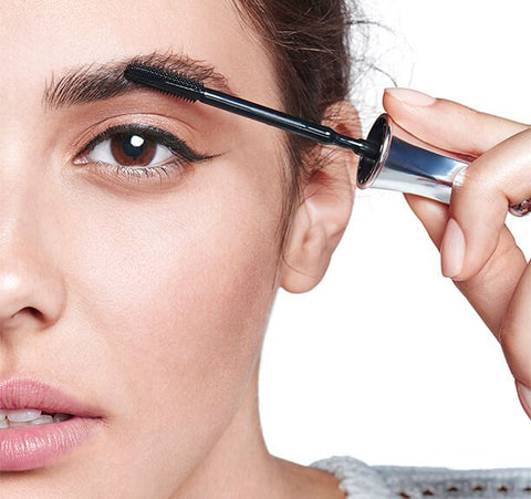 A photo of a person applying The Simple Brow to their eyebrow with the applicator wand