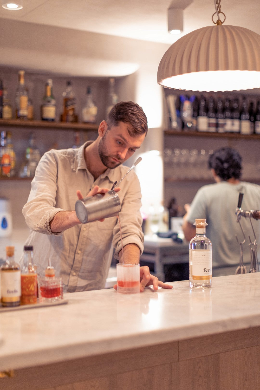 Man at a bar pouring Feels Botanical cocktail