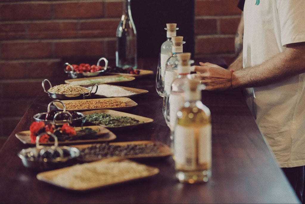 A person standing behind a dark bench top with Feels Botanical bottles and food laid out on platters.