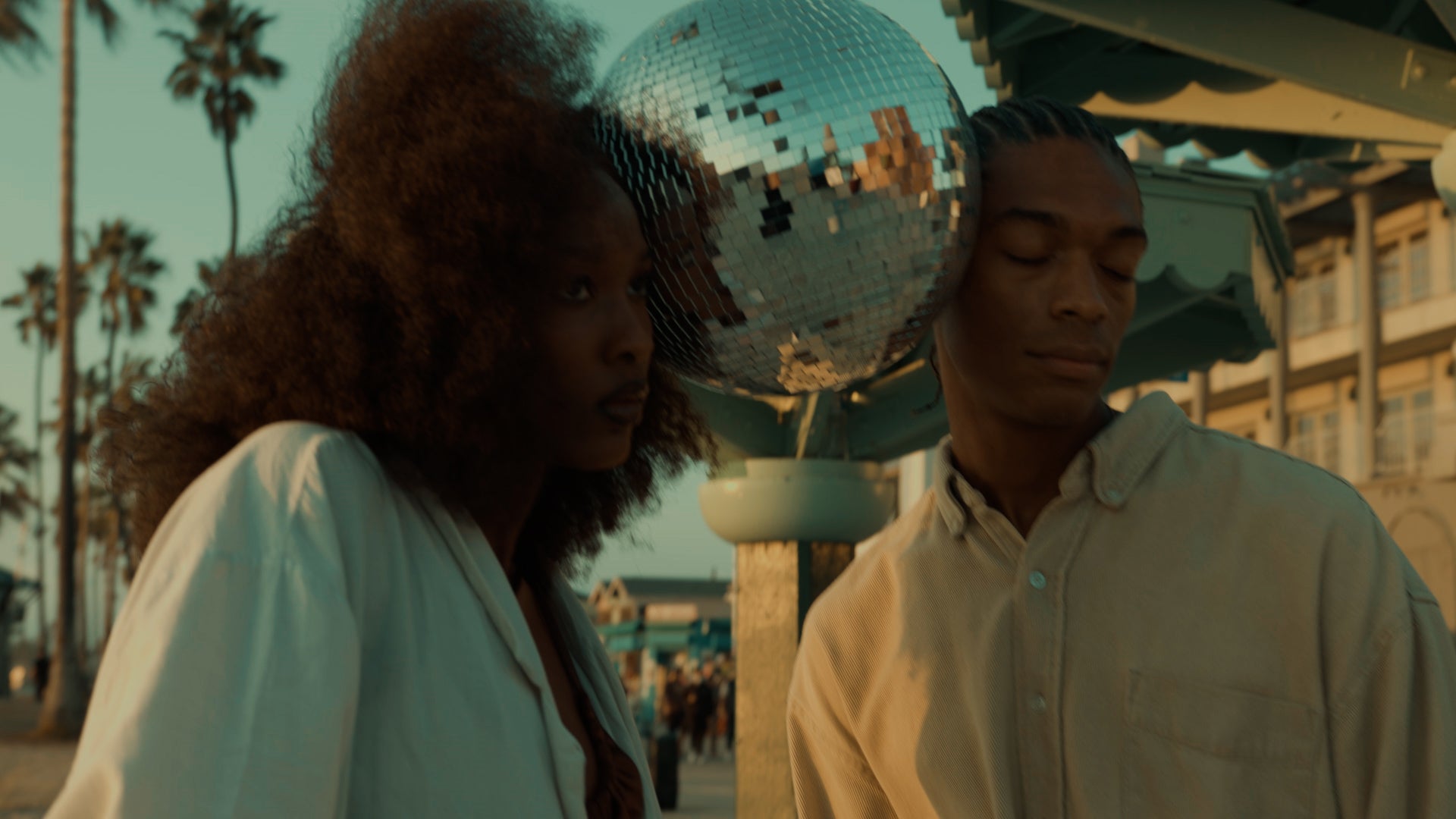 Two people with a disco ball between their heads