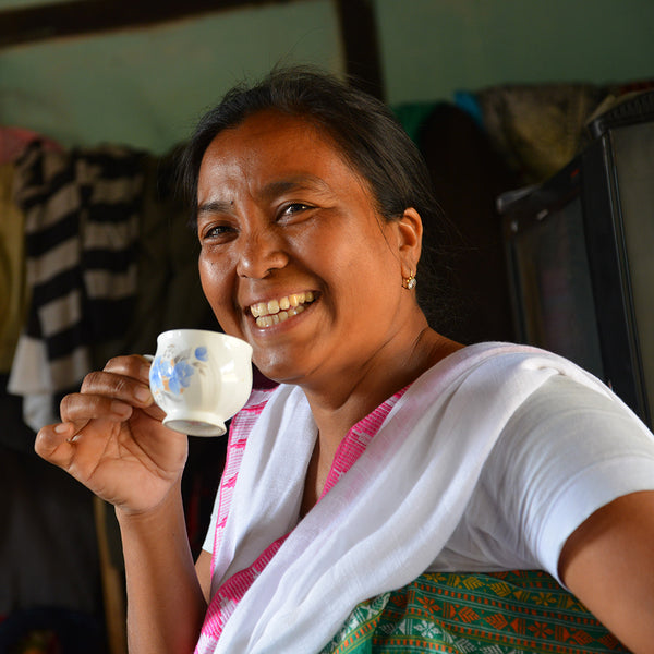 Female tea farmer holding white tea cup smiles