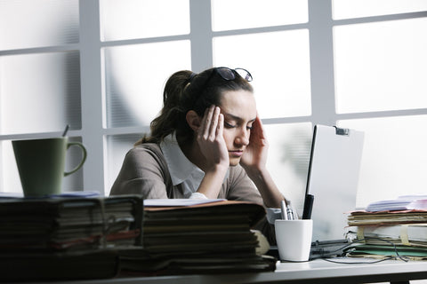 Which Type of Kava Will Work for Your Stress and Anxiousness? Woman sitting at a desk, stressed out from work.