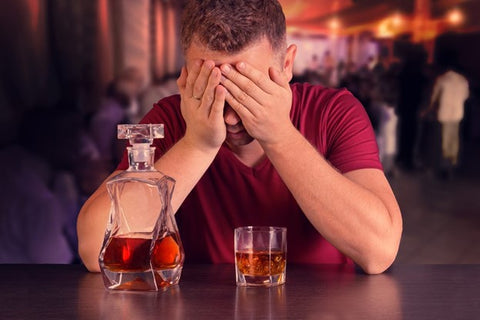 Negative side effects of alcohol. Man sitting at a bar after having drank too much alcohol. 