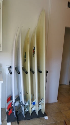 Picture of a white vertical freestanding surfboard rack shown inside a Northern California home.  The surfboard rack is holding several white surfboards of varying sizes.