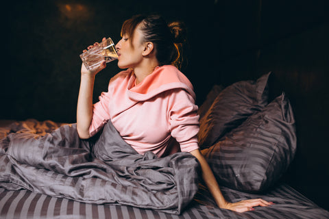 Mujer bebiendo en la cama