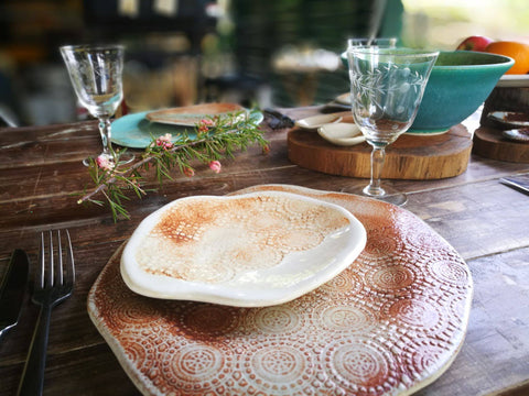 a beautiful table setting with pottery plates and glass cups