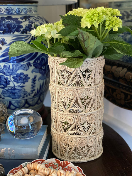 table with handwoven hurricane vase with yellow flowers