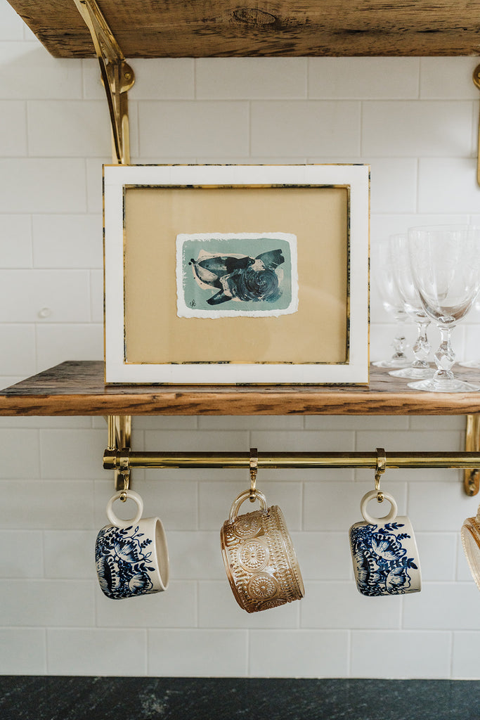 "Goose Pond" abstract painting on paper by Christine Dore Trant framed and styled on a shelf above mugs