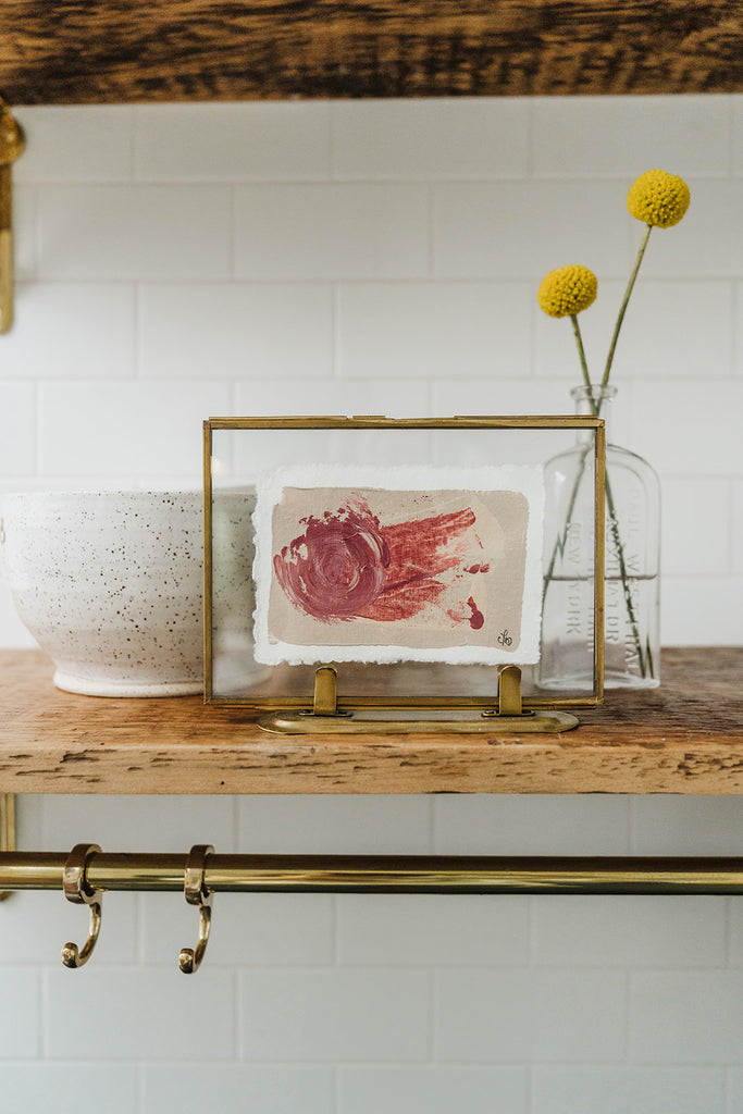 "Trillium Shade" abstract painting on paper in gold floater frame on kitchen shelf with yellow flowers in antique bottle 