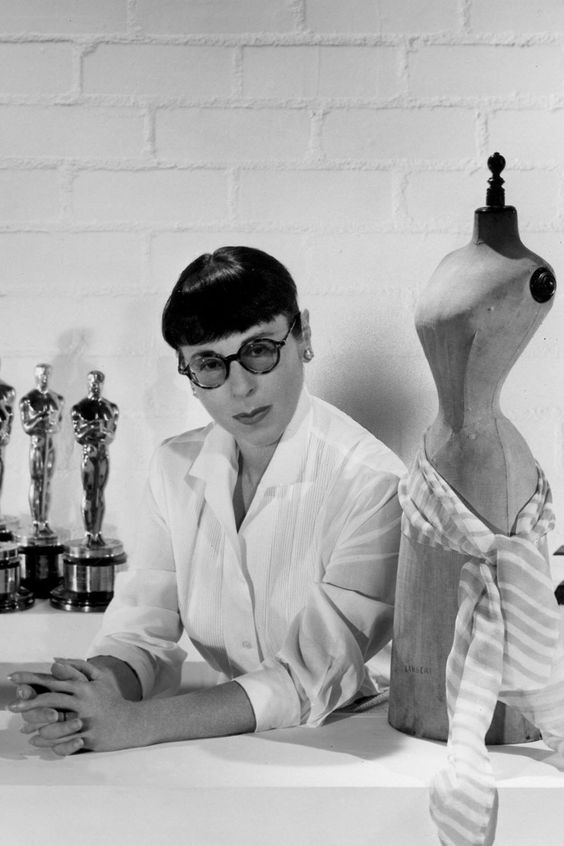 A portrait of Edith Head, known for her blunt fringe and thick rimmed glasses