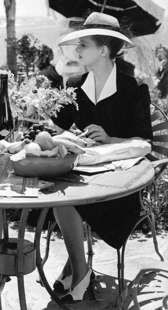 Bette Davis in a black dress on set for Now, Voyager