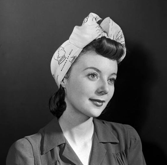 1940s actress Celia Johnson in a headshot for the 1945 film, Brief Encounter. She wears a headscarf in her hair with a classic victory roll. 