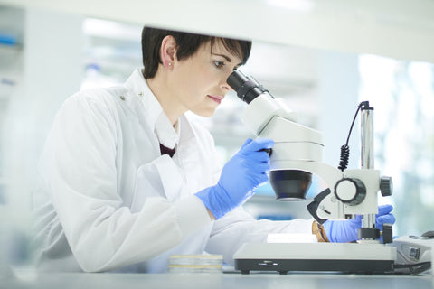 A scientist examining samples under a microscope, representing the research and development behind monolaurin supplements' benefits.